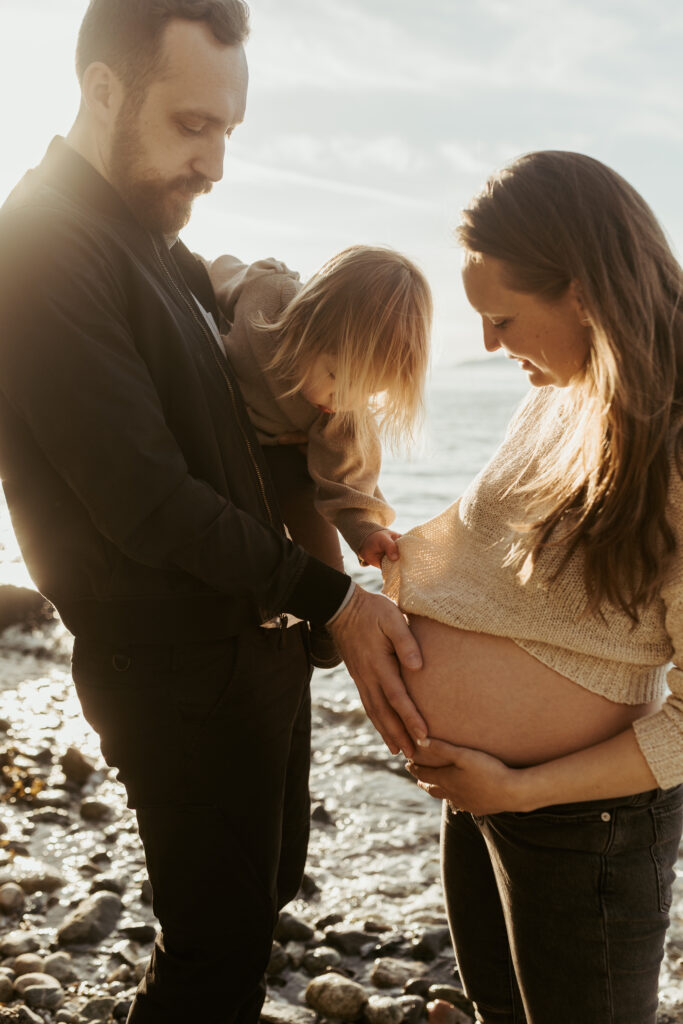 Family with their toddler on the beach at sunset